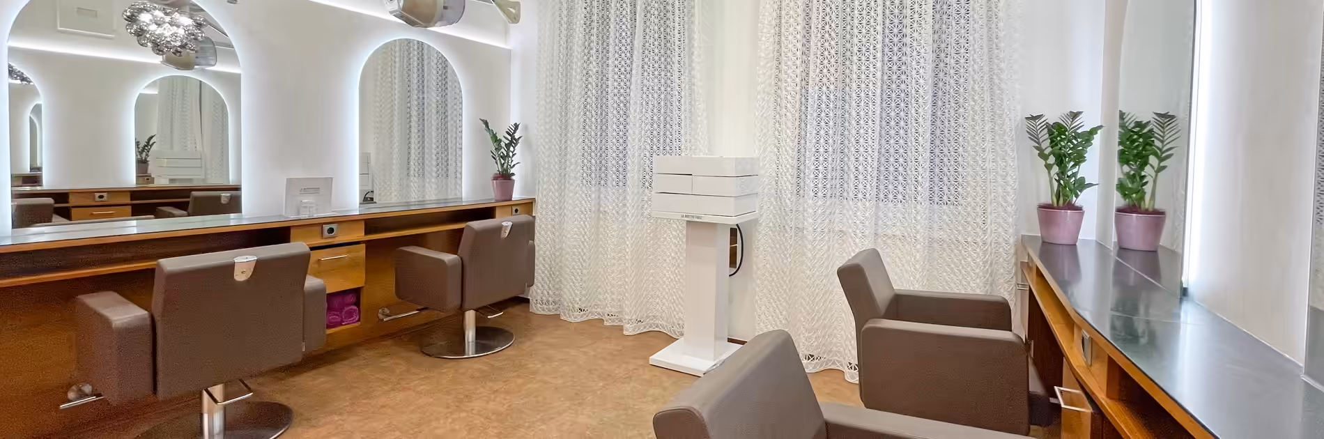 Friseursalon Birgit Gmeiner Raum drei Heller und moderner Friseursalon Birgit Gmeiner mit bequemen braunen Friseurstühlen, großen Spiegeln und stilvoller Beleuchtung in angenehmer Atmosphäre.