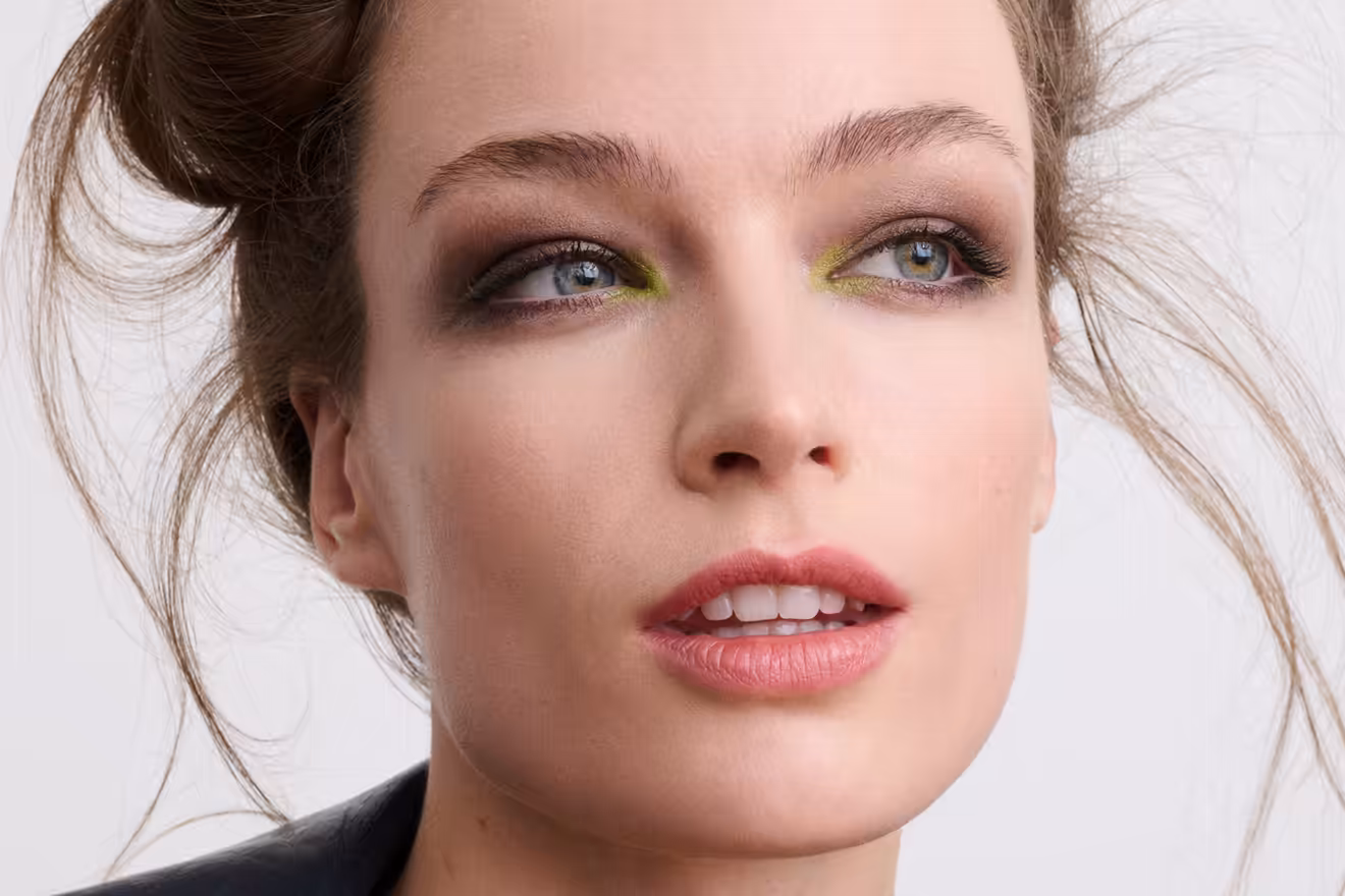 Nahaufnahme einer Frau mit Look Nocturne Make-up, das rauchige Töne mit leuchtenden grünen Akzenten an den inneren Augenwinkeln kombiniert.